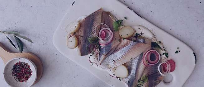 Филе рыбы с молодым картофелем и маринованным луком на белой тарелке