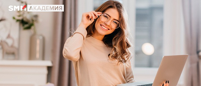 Улыбающаяся девушка в очках за ноутбуком — баннер SMM Академии